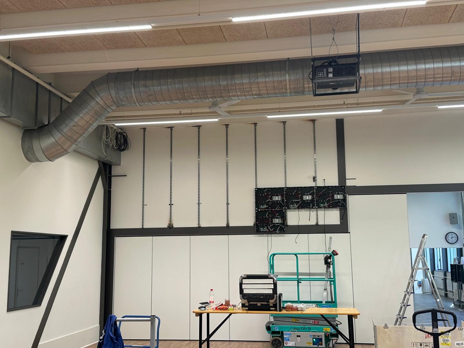 Die ersten vier LED-Cabinets hängen an den Montageschienen, davor Scherenbühne und Werkbank