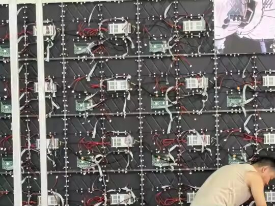 Rückseite einer aufgebauten LED-Wand: sichtbar sind Empfängerkarten, Flachbandkabel und die rot-schwarze Stromverteilung auf mehreren Cabinet-Reihen